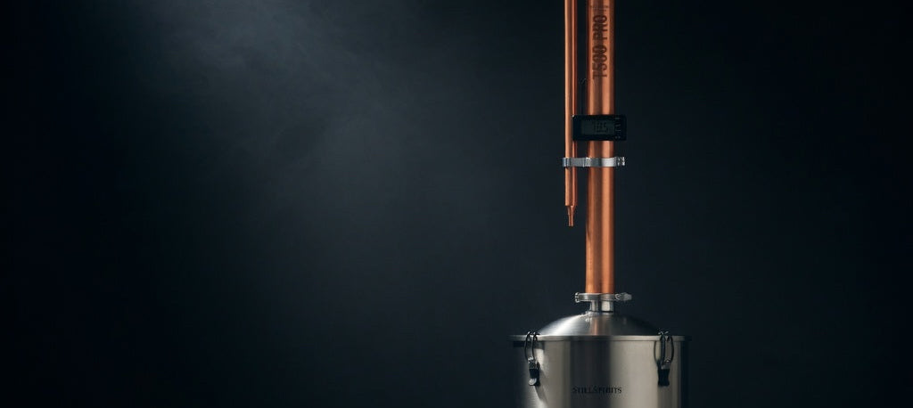 Distillation apparatus with copper column and stainless steel base on a dark background