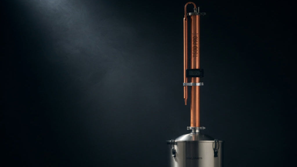 Distillation apparatus with copper column and stainless steel base on a dark background